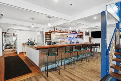 a open kitchen with stainless steel appliances kitchen island granite countertop a table chairs and wooden floor