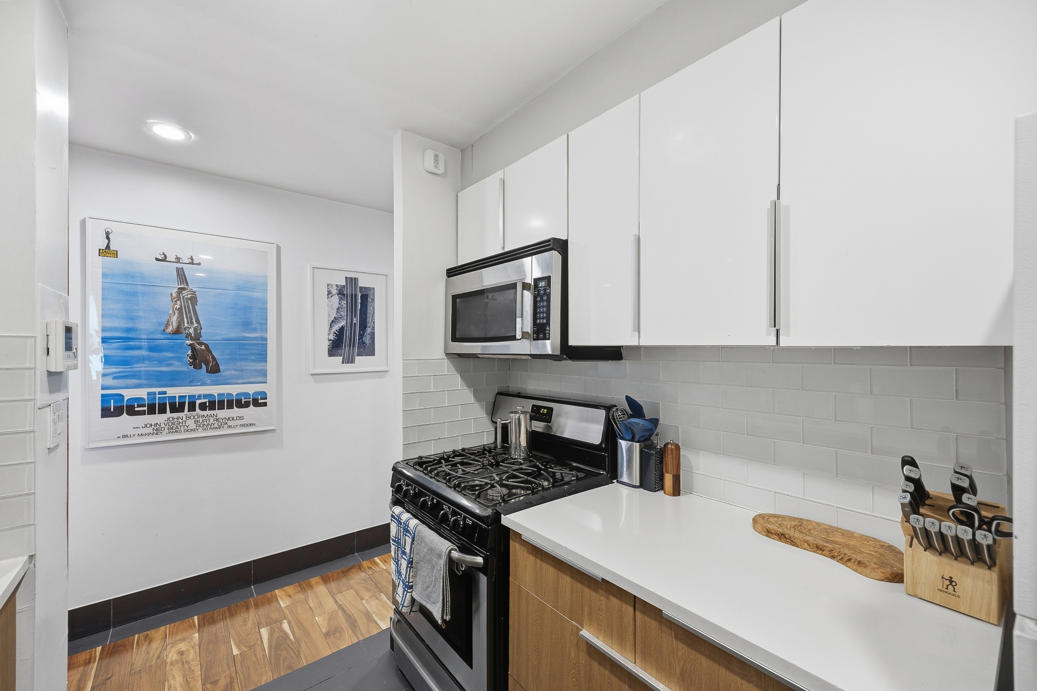 179 Grand Street, Unit 2F Manhattan, NY 10013 - Photo 4 of 11 a kitchen with stainless steel appliances a stove a microwave and white cabinets
