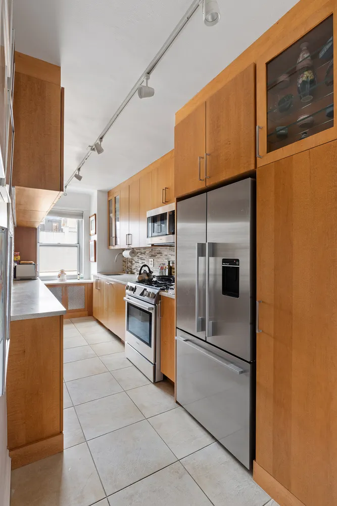 a kitchen with stainless steel appliances granite countertop a refrigerator a stove and a sink with wooden floor