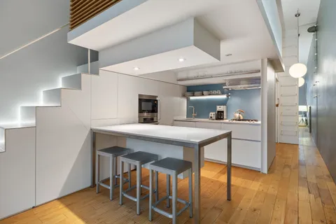 a kitchen with stainless steel appliances a dining table chairs and wooden floor