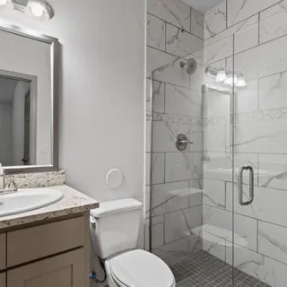 a bathroom with a granite countertop toilet sink shower and mirror
