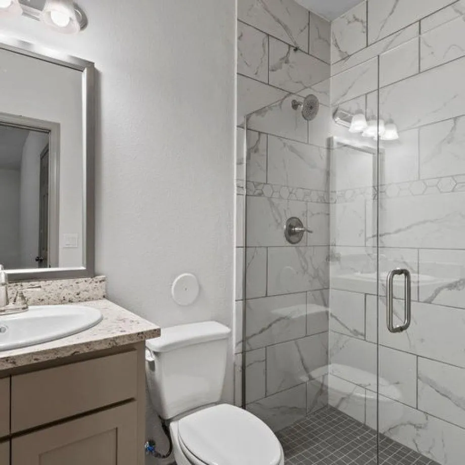 a bathroom with a granite countertop toilet sink shower and mirror