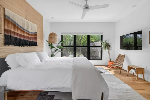 a bedroom with a bed a large window and wooden floor