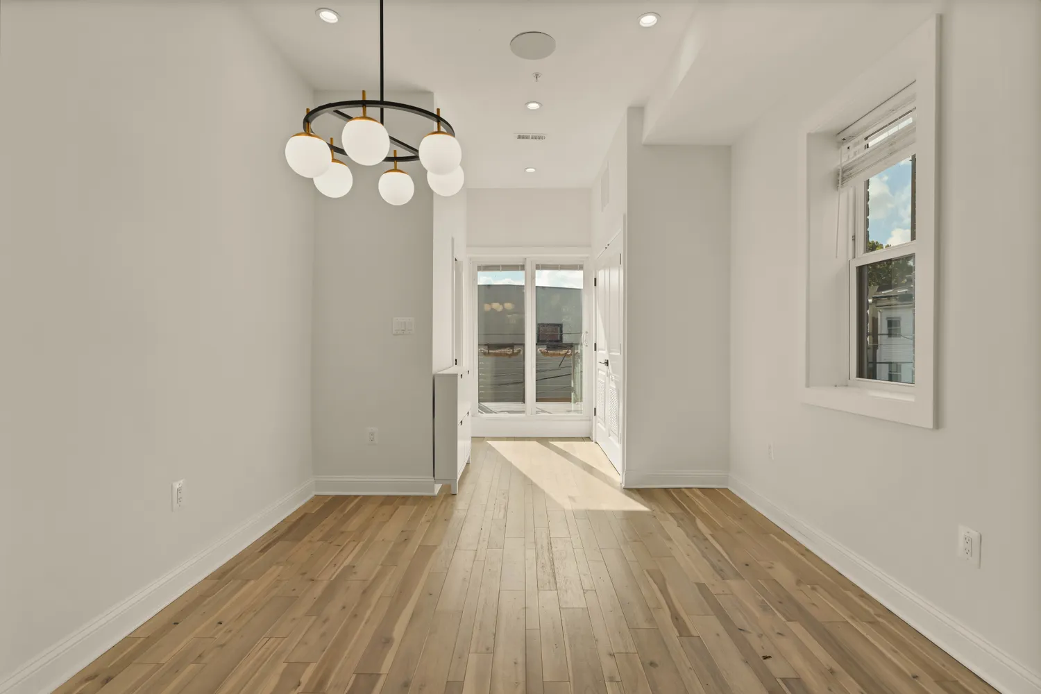 a view of an empty room with wooden floor and windows