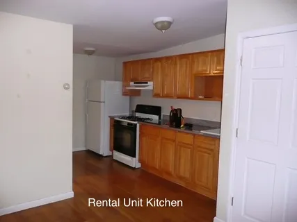 a kitchen with granite countertop a refrigerator a stove top oven with wooden floor