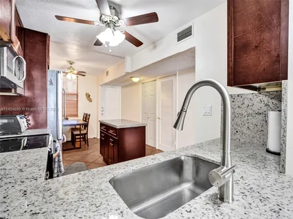 a kitchen with stainless steel appliances kitchen island granite countertop a refrigerator a stove and a sink with wooden floor