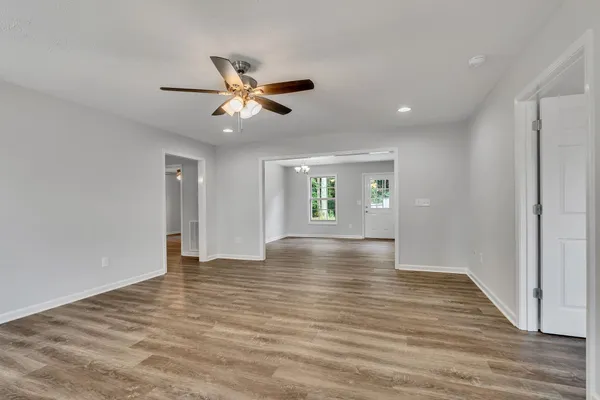a view of an empty room with window and wooden floor