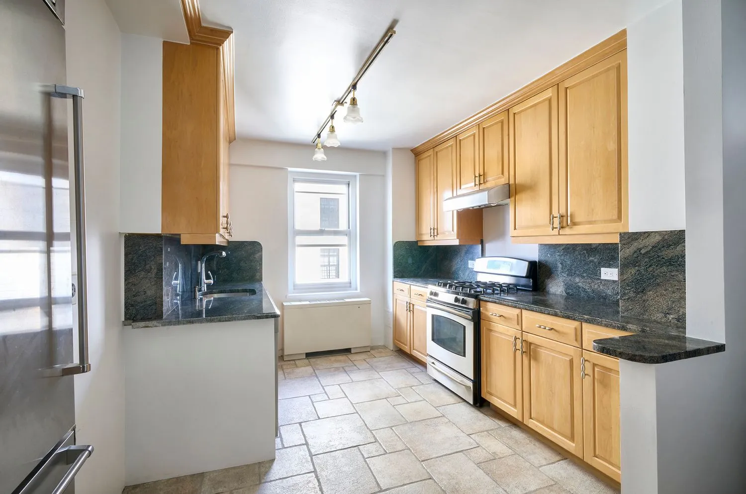 a kitchen with stainless steel appliances granite countertop a stove a sink and a refrigerator