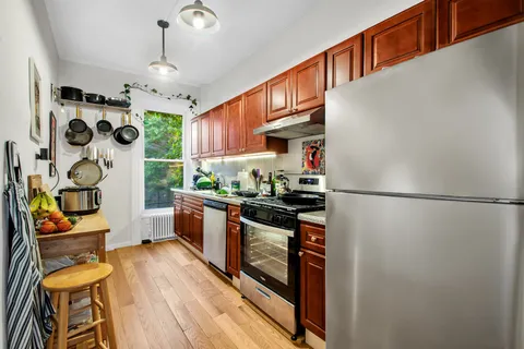 a kitchen with stainless steel appliances granite countertop a refrigerator a stove a sink and a dining table with wooden floor