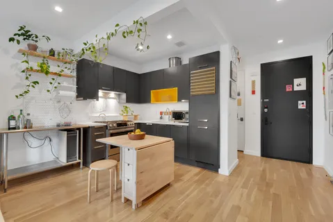 a kitchen with stainless steel appliances a stove a refrigerator a sink a dining table and chairs