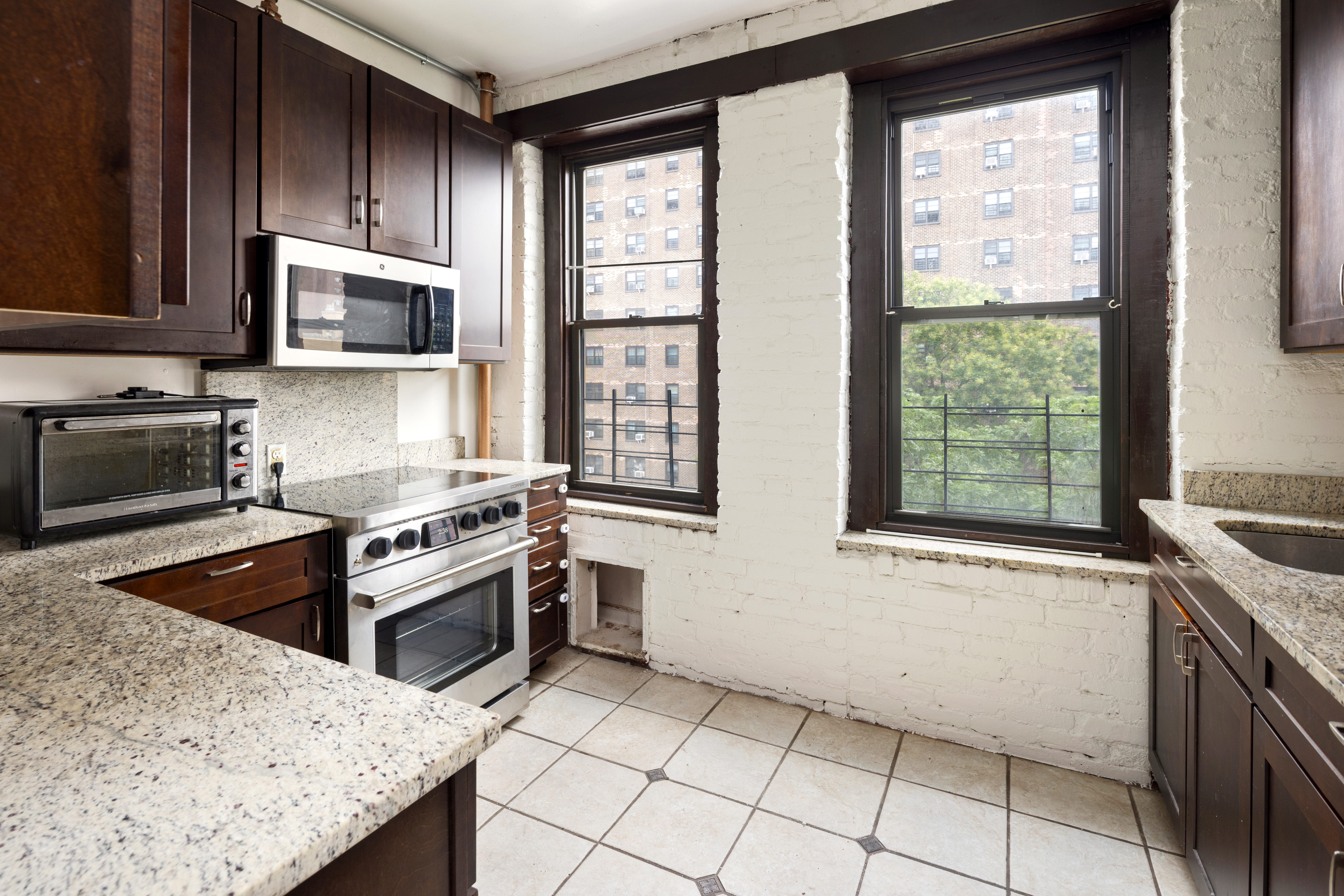 501 West 156th Street, Unit 44 Manhattan, NY 10032 - Photo 3 of 8 a kitchen with granite countertop a stove a sink and a microwave