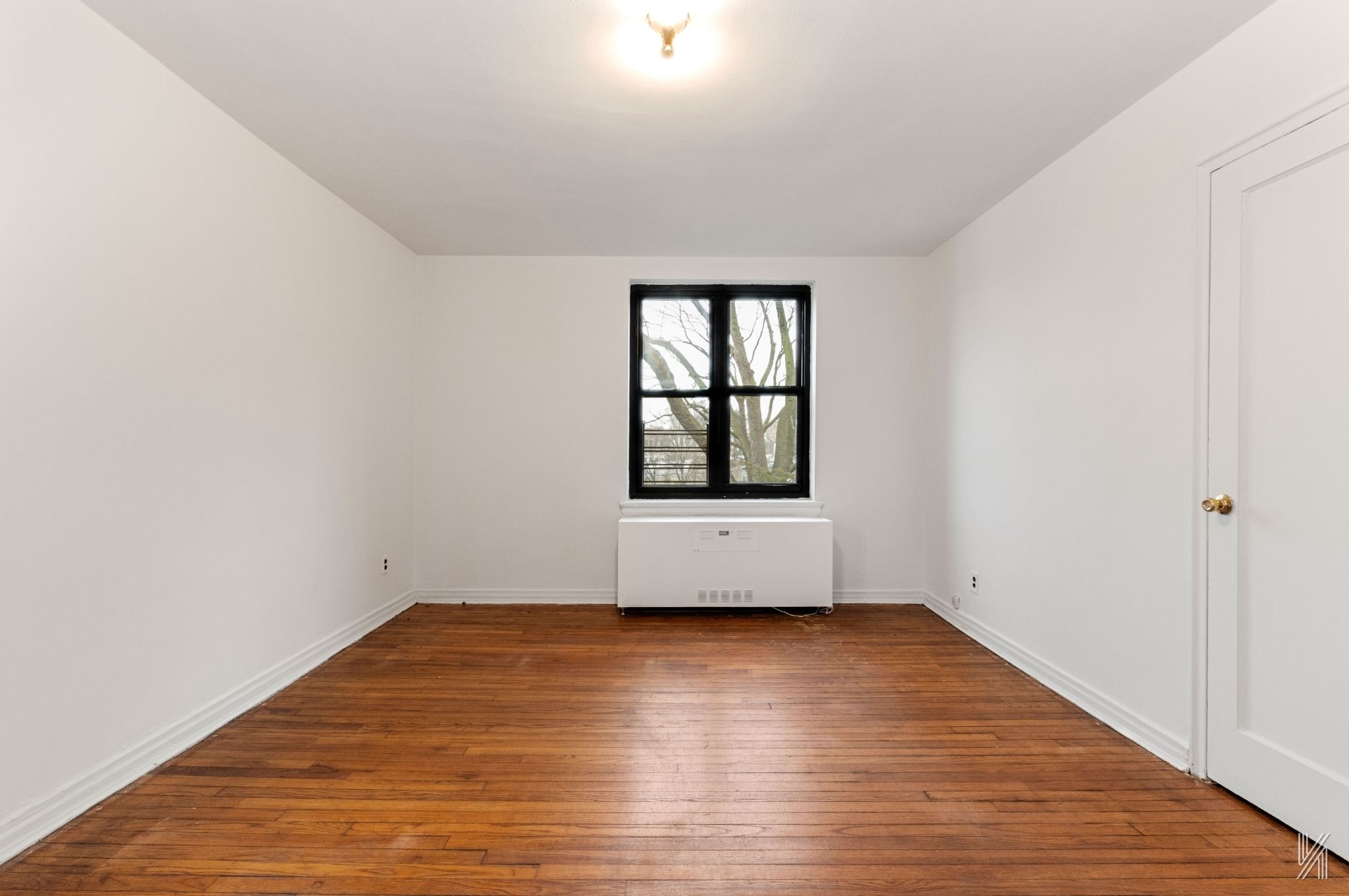 22-60 79th Street, Unit 3E Queens, NY 11370 - Photo 10 of 17 an empty room with wooden floor and windows