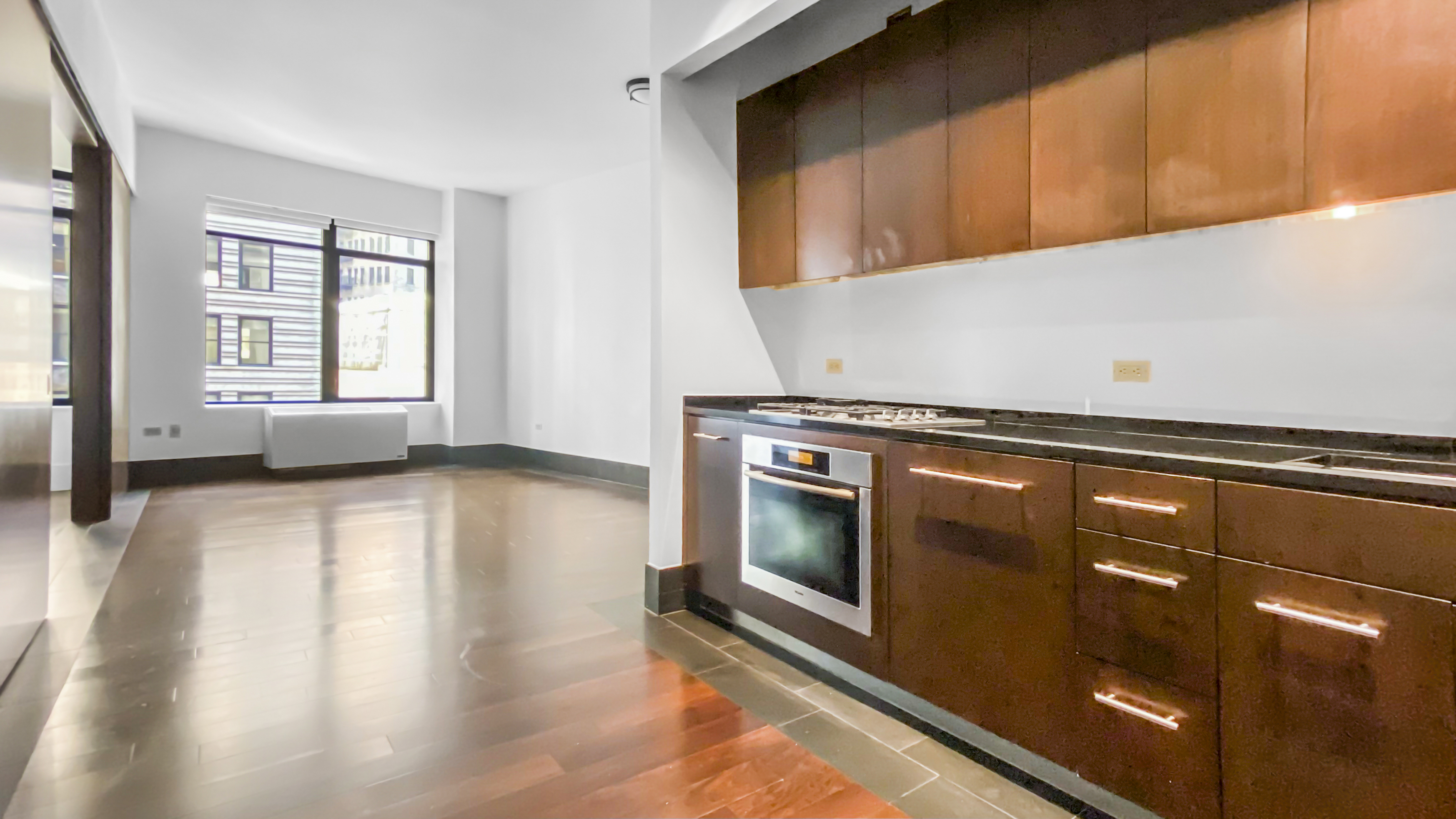 40 Broad Street, Unit 16E Manhattan, NY 10004 - Photo 6 of 16 a kitchen with granite countertop a stove and a microwave