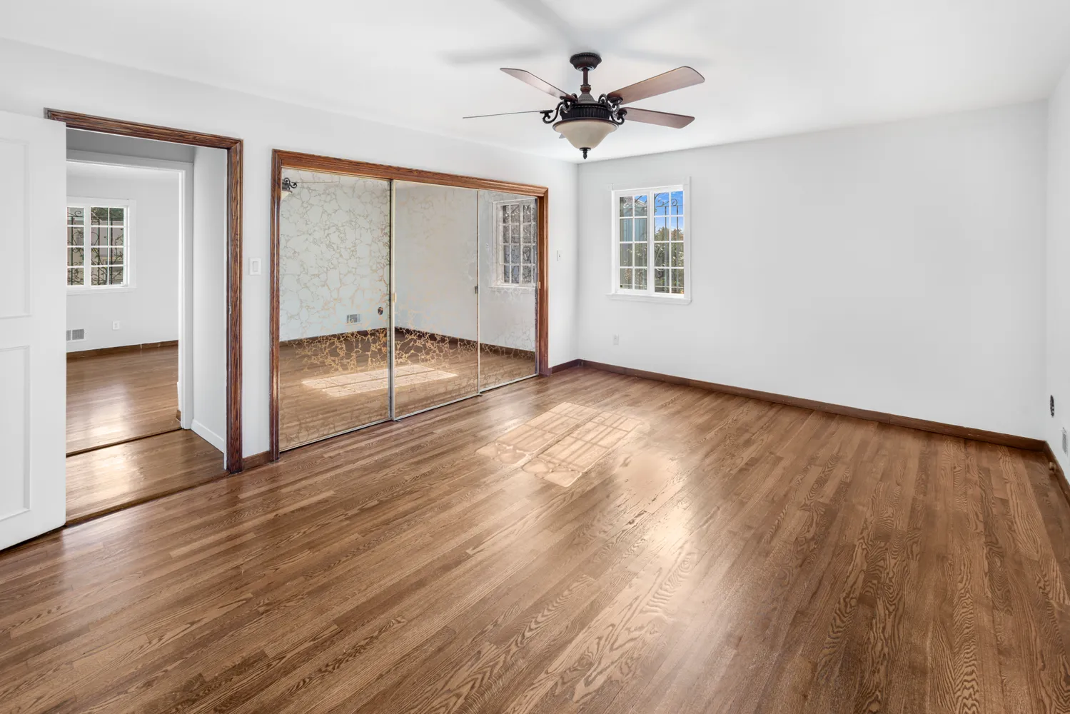 a view of empty room with wooden floor and fan