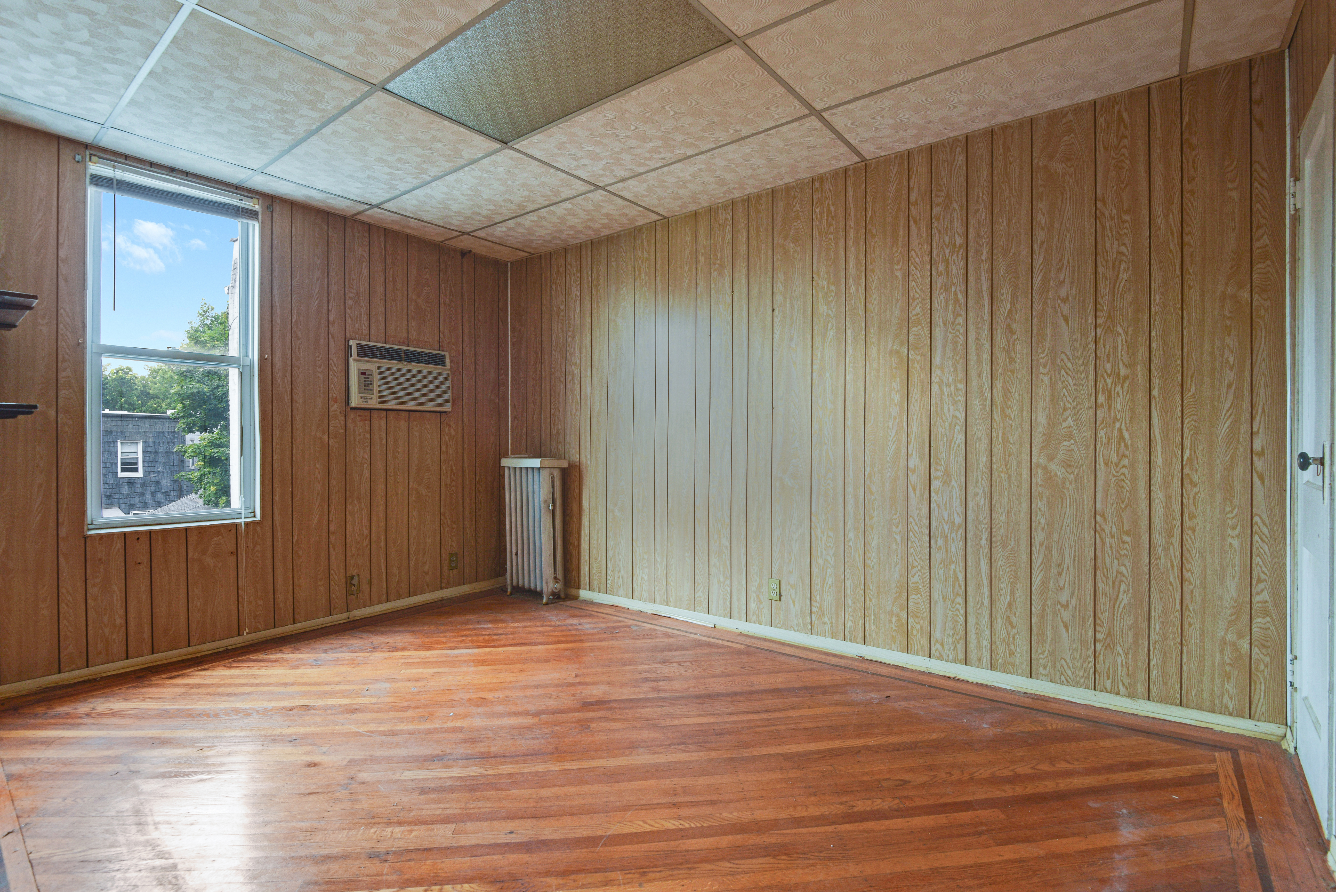 75-36 60th Lane Queens, NY 11385 - Photo 11 of 18 a view of an empty room with wooden floor and a window