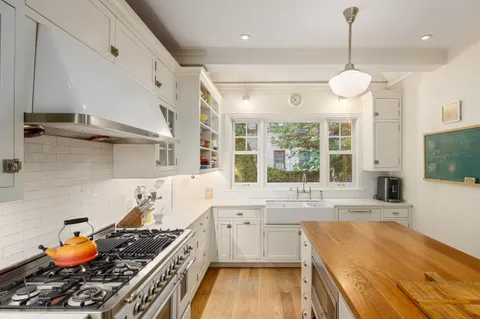 a kitchen with a stove a sink and a wooden floor