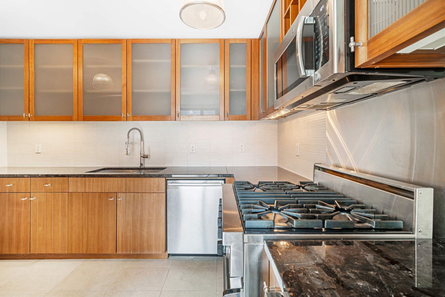 250 East 53rd Street, Unit 1001 Manhattan, NY 10022 - Photo 6 of 18 a kitchen with stainless steel appliances granite countertop a stove and a sink