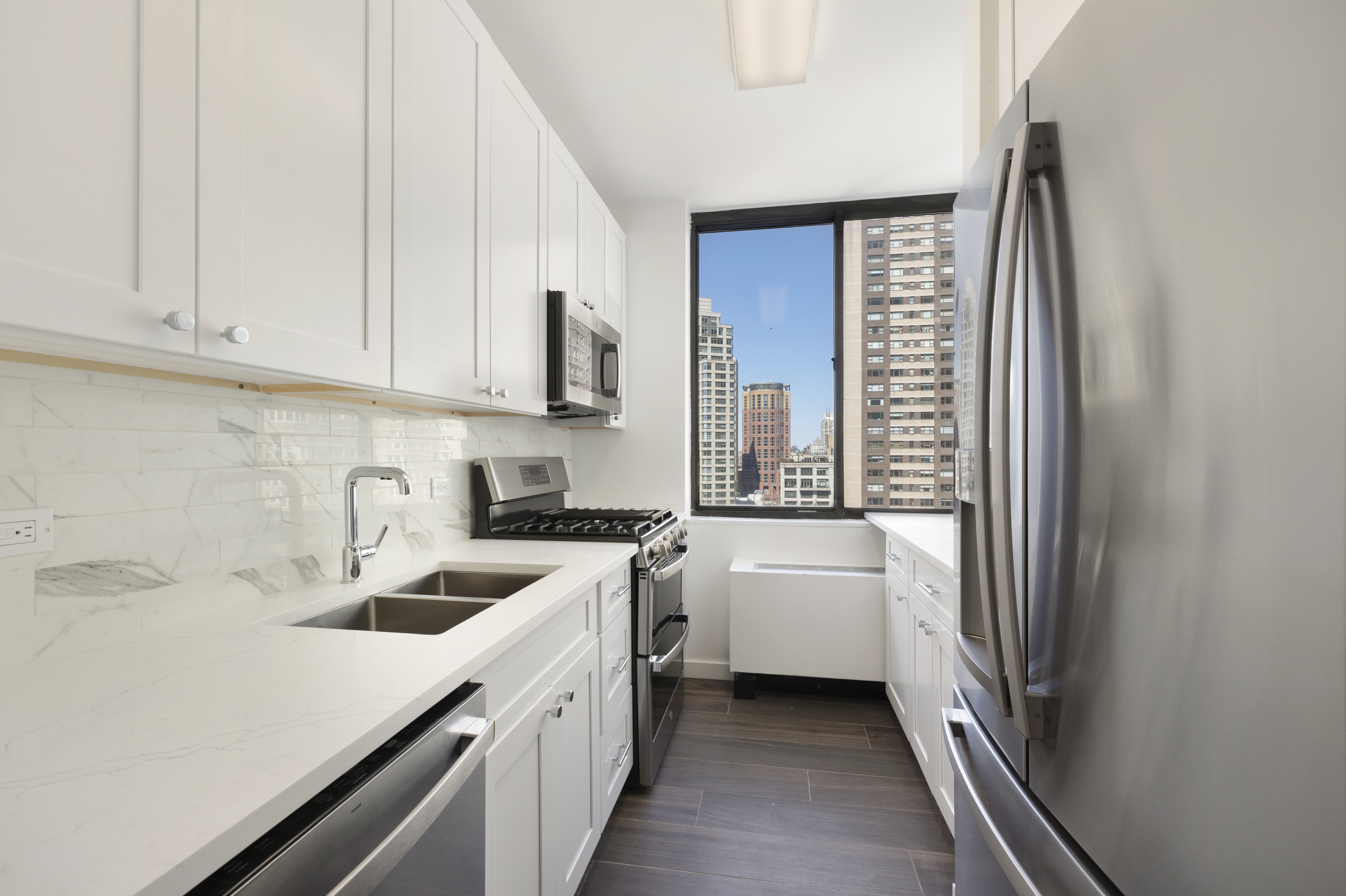 62 West 62nd Street, Unit 18A Manhattan, NY 10023 - Photo 6 of 16 a kitchen with a sink a stove and cabinets