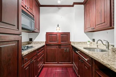 a kitchen with granite countertop a sink stove and cabinets