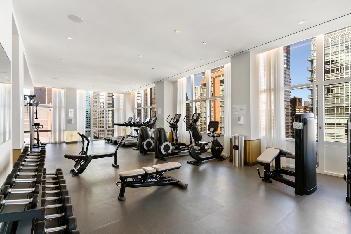 305 East 51st Street, Unit 11D Manhattan, NY 10022 - Photo 12 of 18 a view of a room with gym equipment and floor to ceiling window