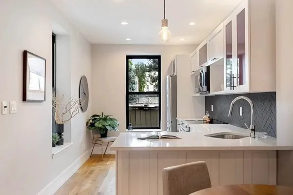 a dining hall with stainless steel appliances granite countertop a sink a stove and a wooden floors