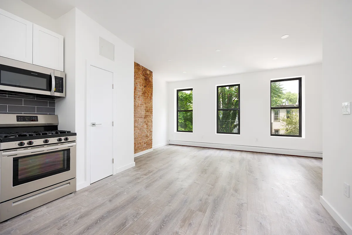 601 Decatur Street Brooklyn, NY 11233 - Photo 2 of 5 an empty room with wooden floor stainless steel appliances and windows