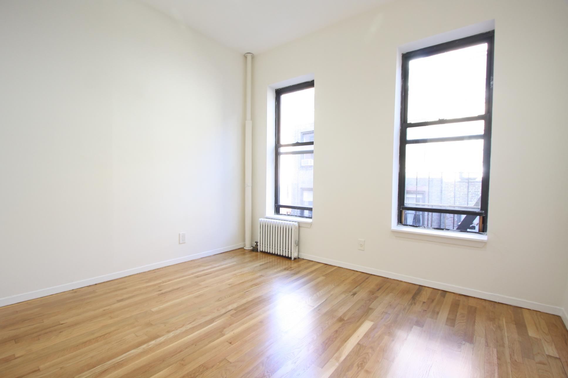 435 East 75th Street, Unit 13 Manhattan, NY 10021 - Photo 3 of 6 an empty room with wooden floor and windows