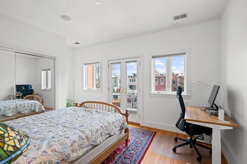 a bedroom with a bed a desk and chair with wooden floor