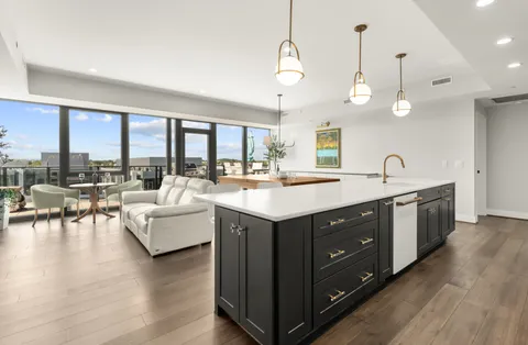 a kitchen with a stove kitchen island living room and couches with wooden floor