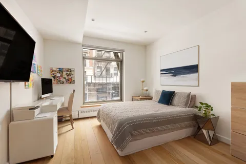 a bedroom with a bed a flat screen tv and a couch