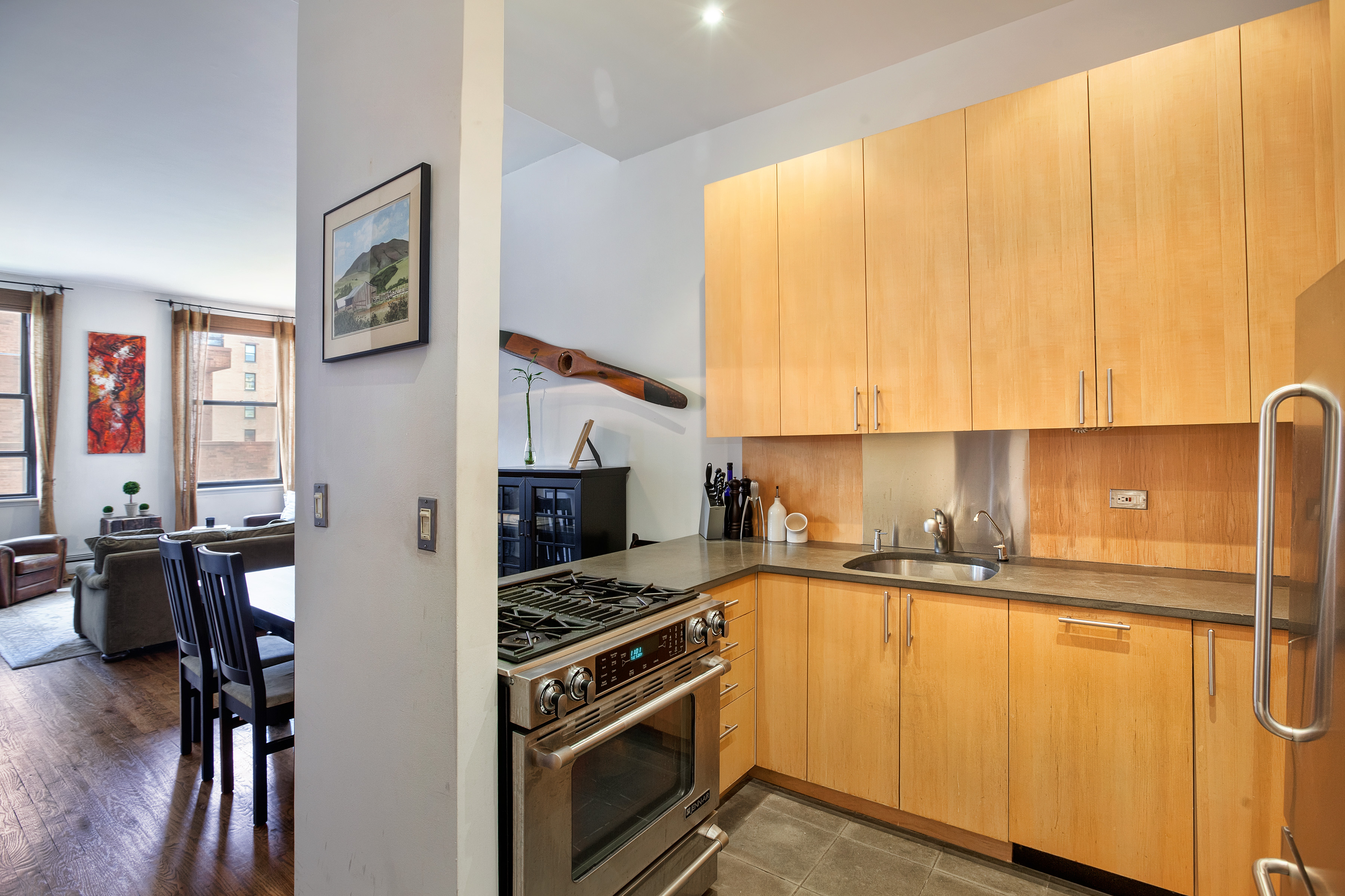 250 Mercer Street, Unit D603 Manhattan, NY 10012 - Photo 13 of 20 a kitchen with stainless steel appliances a stove a sink and white cabinets with wooden floor