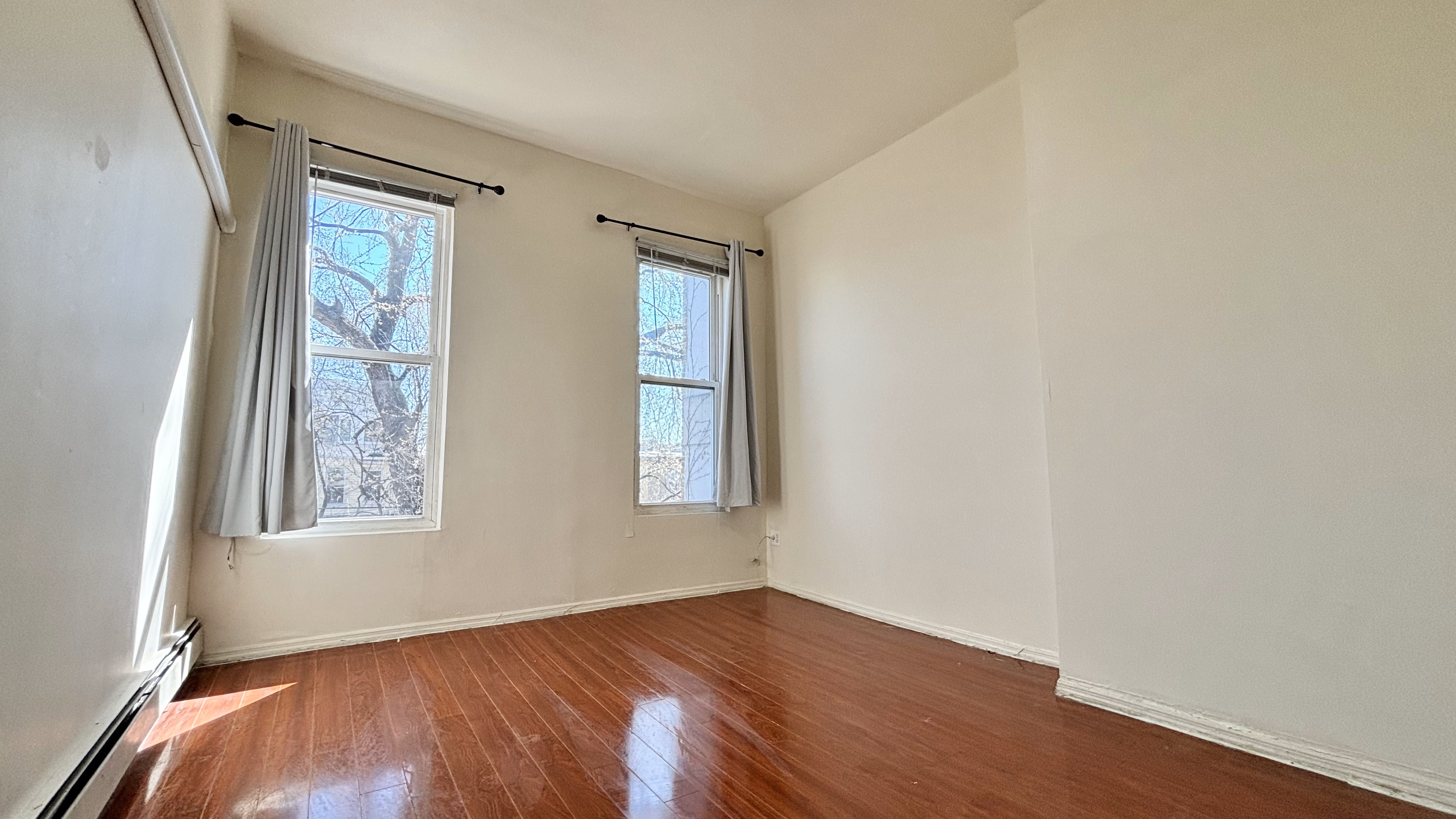 74 Himrod Street, Unit 2 Brooklyn, NY 11221 - Photo 7 of 16 an empty room with wooden floor and windows