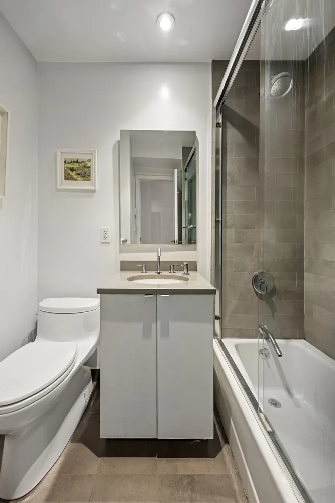 a bathroom with a granite countertop sink a toilet and shower