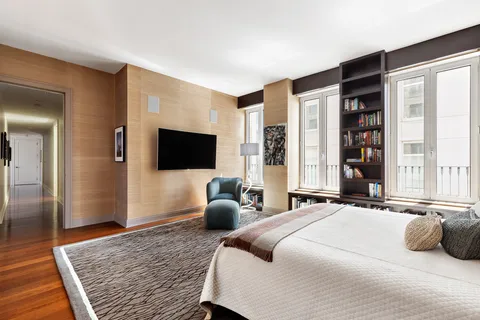 a bedroom with a bed flat screen tv and a large window