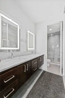 a spacious bathroom with a granite countertop sink a toilet a mirror and a shower