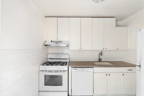 a kitchen with granite countertop white cabinets and white appliances
