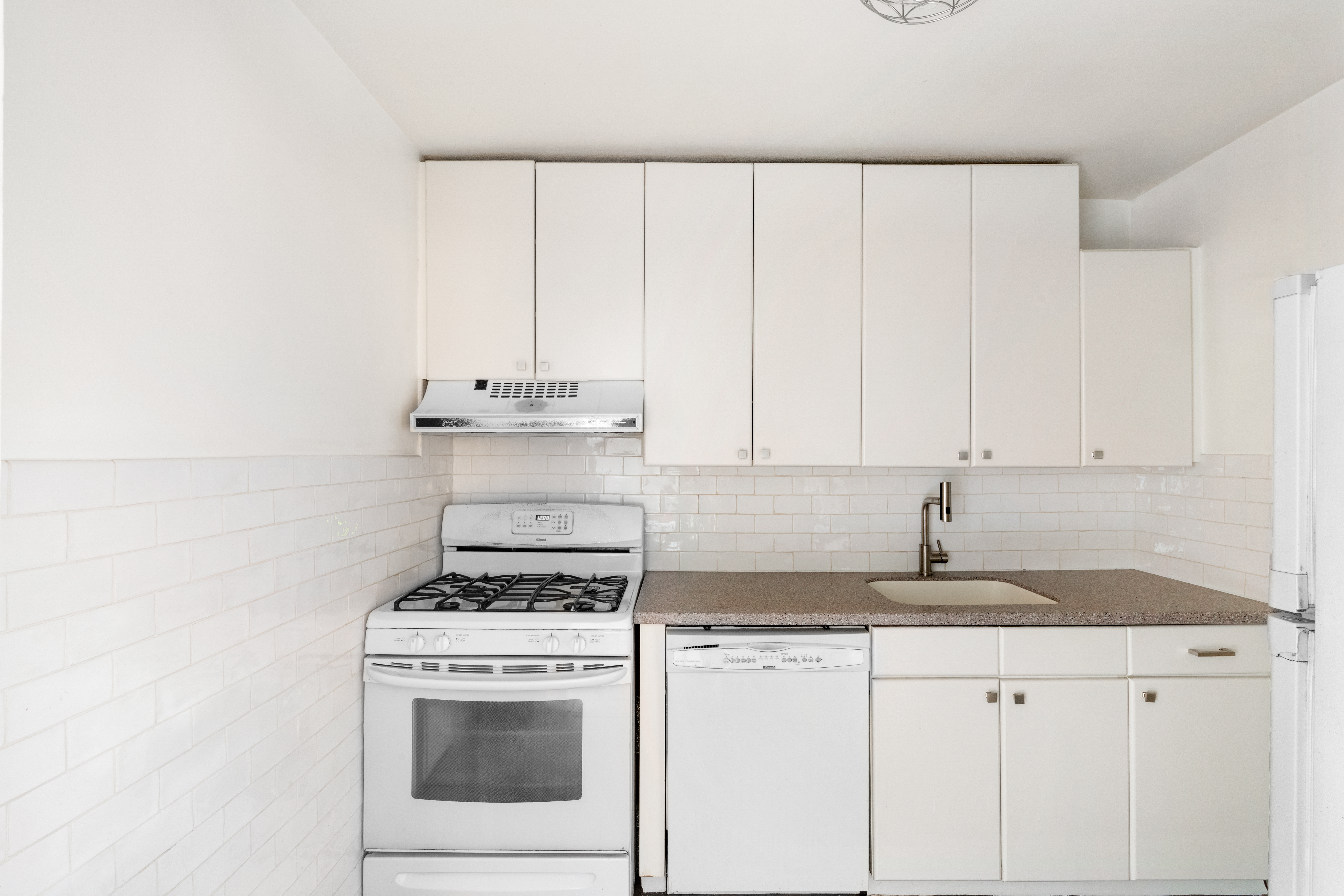 315 East 70th Street, Unit 6K Manhattan, NY 10021 - Photo 8 of 16 a kitchen with granite countertop white cabinets and white appliances