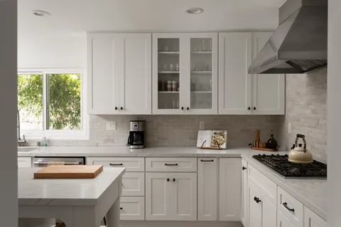 a kitchen with white cabinets and window