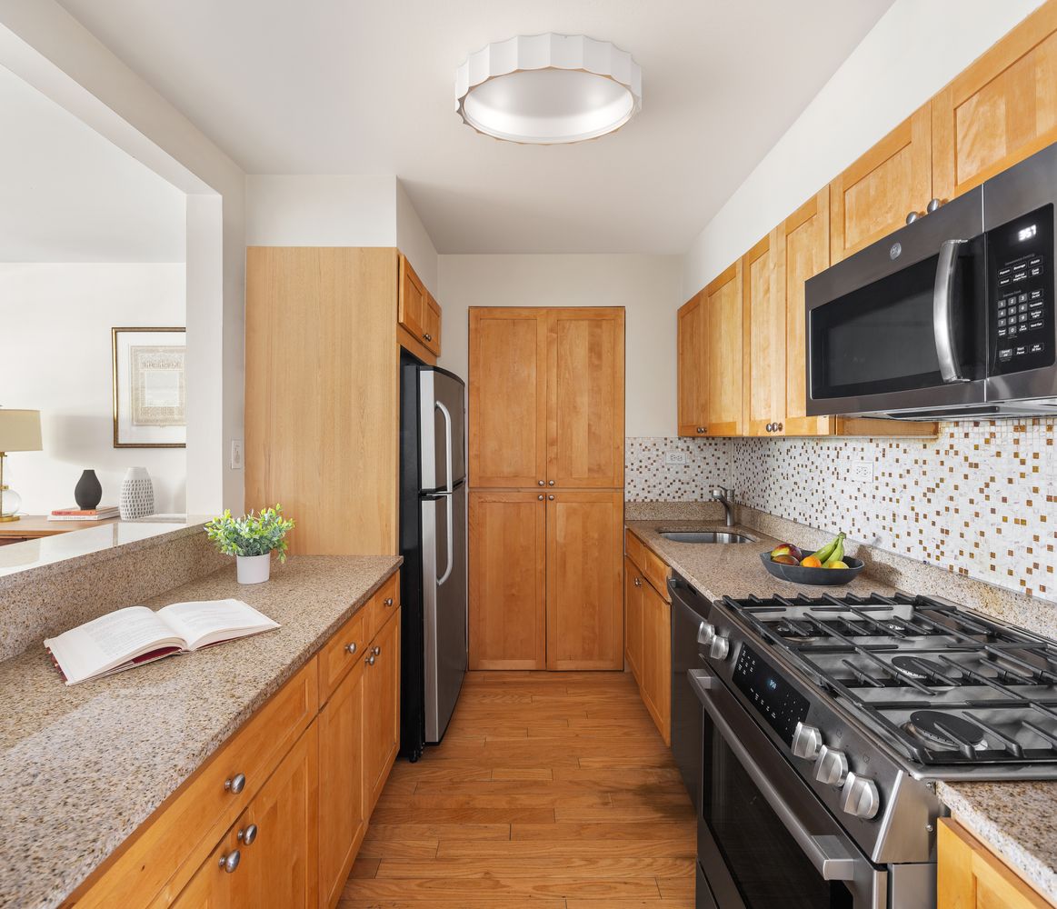 a kitchen with stainless steel appliances granite countertop a stove a sink and a microwave