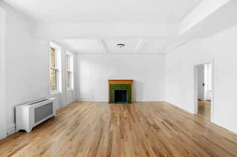 a view of empty room with wooden floor and fireplace