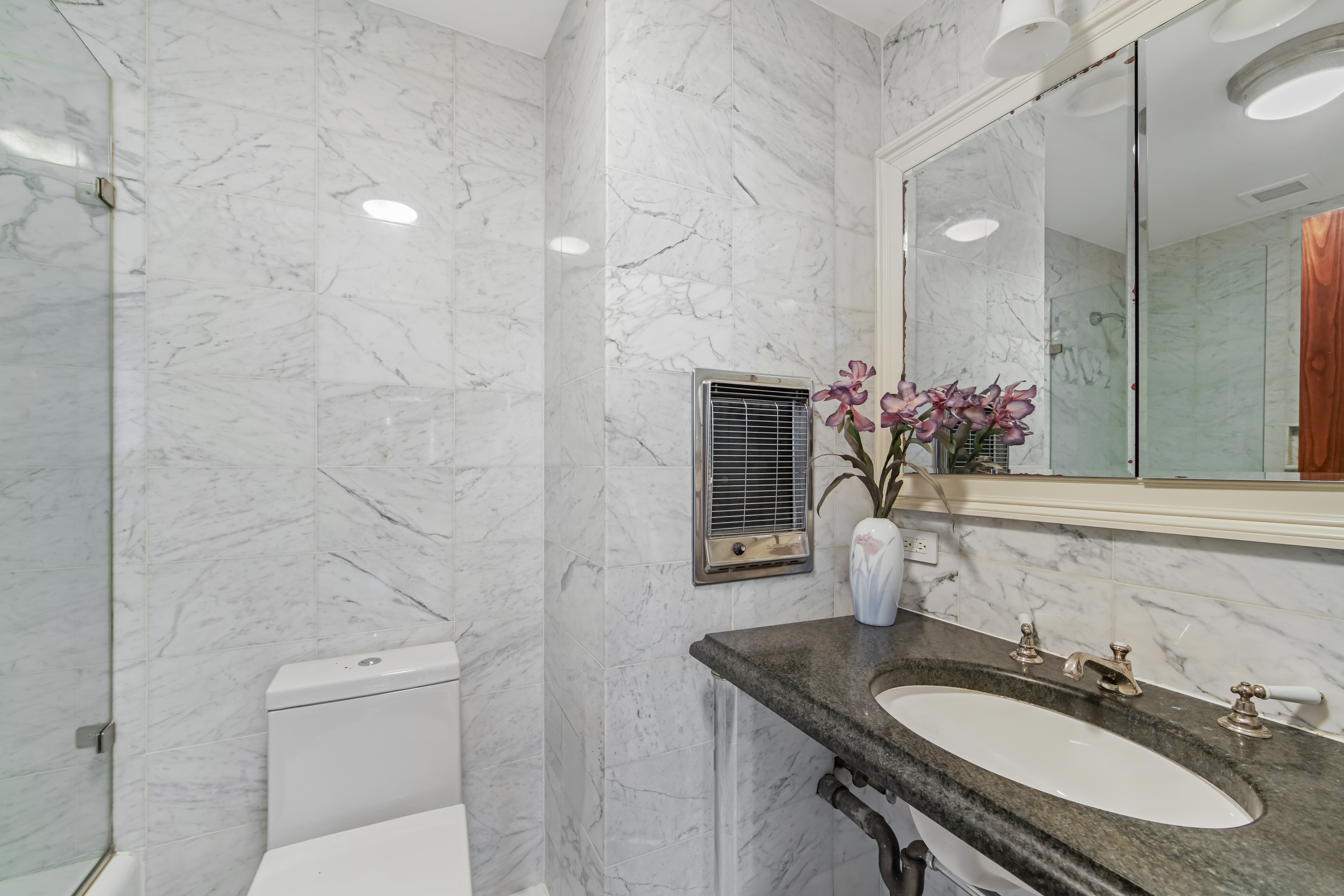 425 East 58th Street, Unit 29C Manhattan, NY 10022 - Photo 8 of 9 a bathroom with a granite countertop sink a toilet and shower