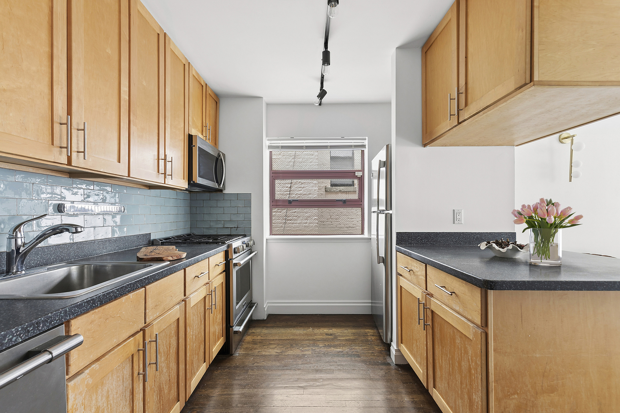 217 East 7th Street, Unit 5CD Manhattan, NY 10009 - Photo 3 of 11 a kitchen with stainless steel appliances granite countertop a sink stove and cabinets