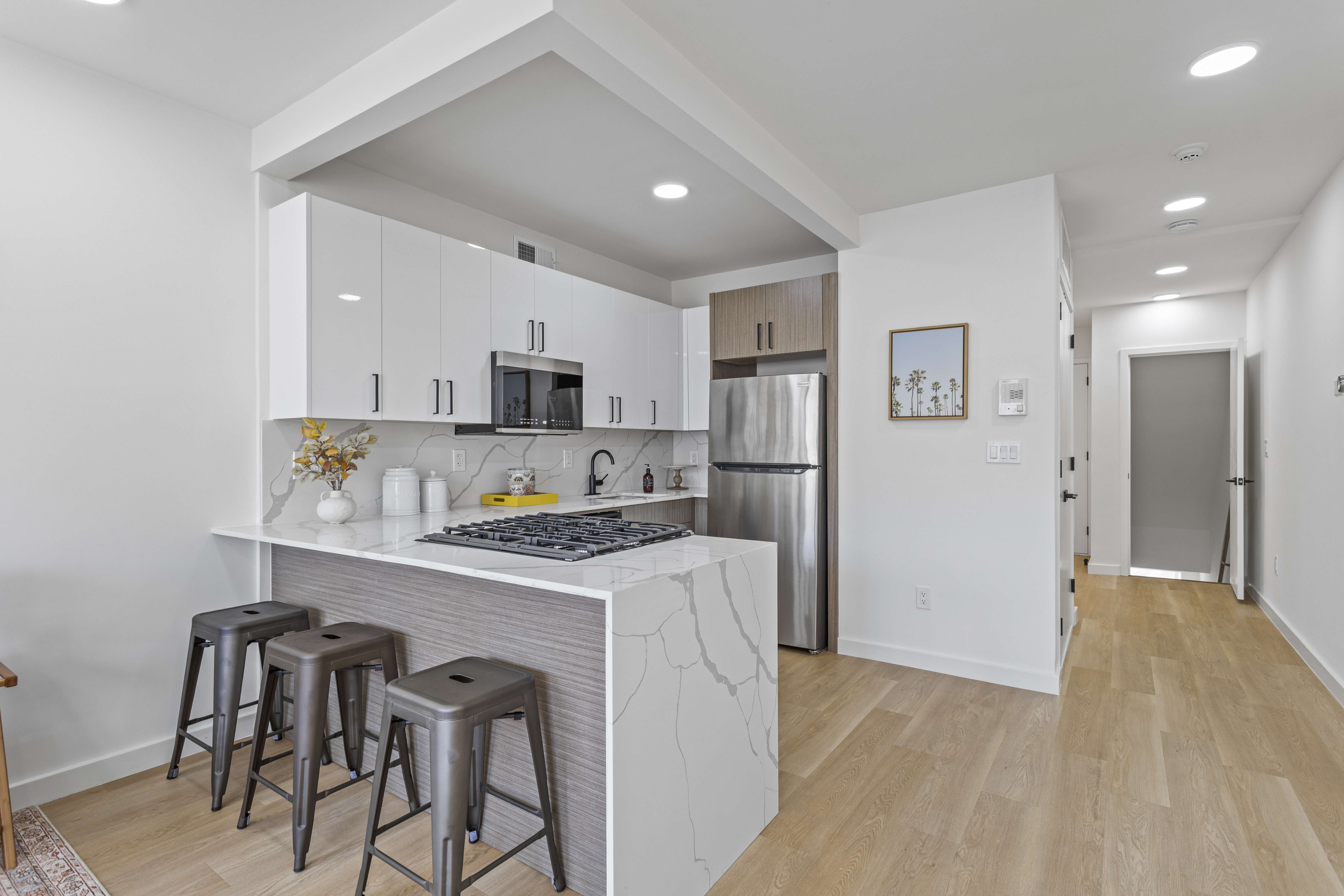 3112 Emmons Avenue, Unit 3140A-2 Brooklyn, NY 11235 - Photo 4 of 13 a kitchen with stainless steel appliances a refrigerator a stove a sink dishwasher and white cabinets with wooden floor