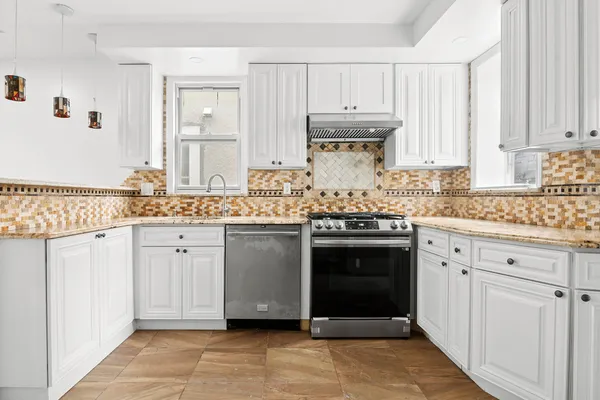 a kitchen with granite countertop white cabinets and stainless steel appliances