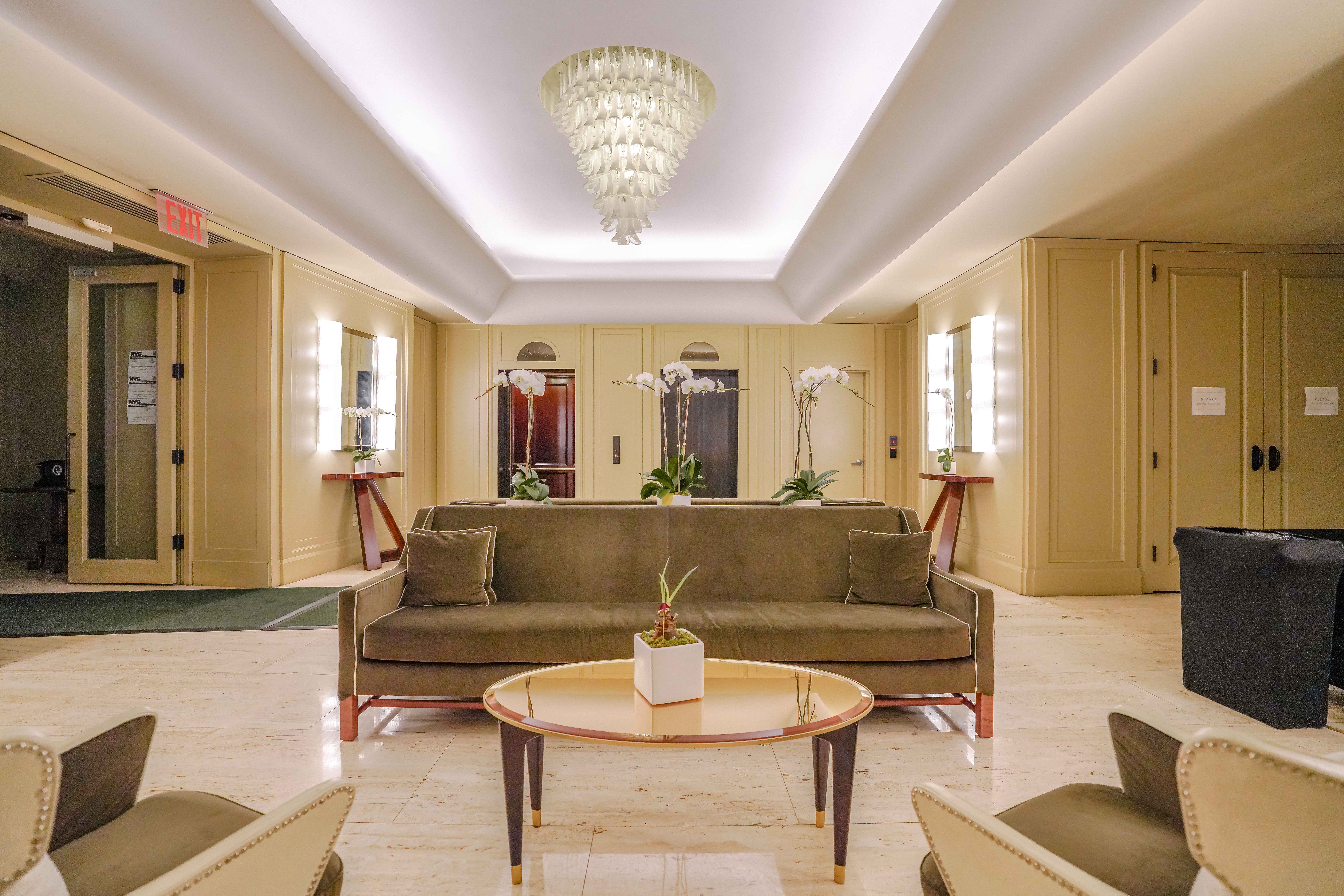 55 Wall Street, Unit PH910 Manhattan, NY 10005 - Photo 17 of 19 a living room with a couch and a chandelier