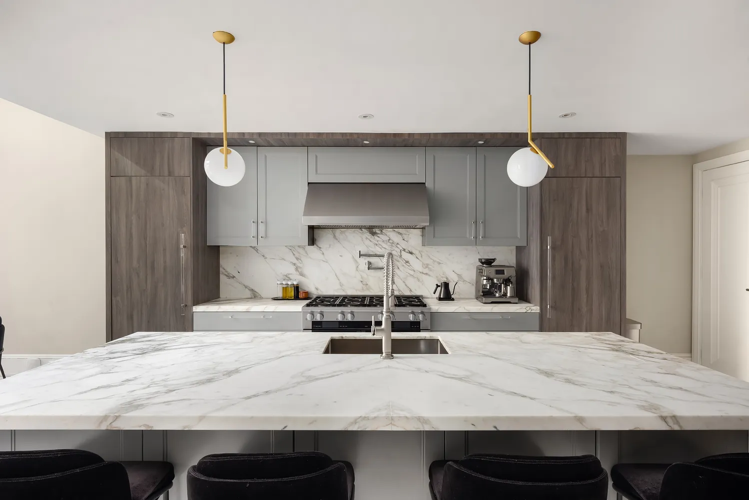 a large white kitchen with a sink and a stove top oven with wooden floor