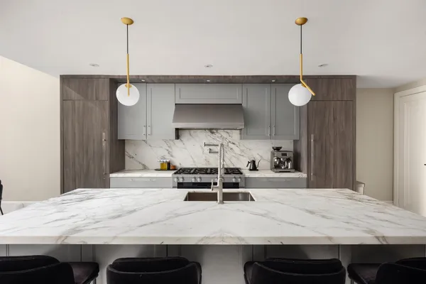 a large white kitchen with a sink and a stove top oven with wooden floor