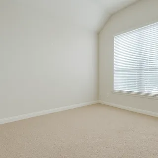 an empty room with chandelier fan and windows