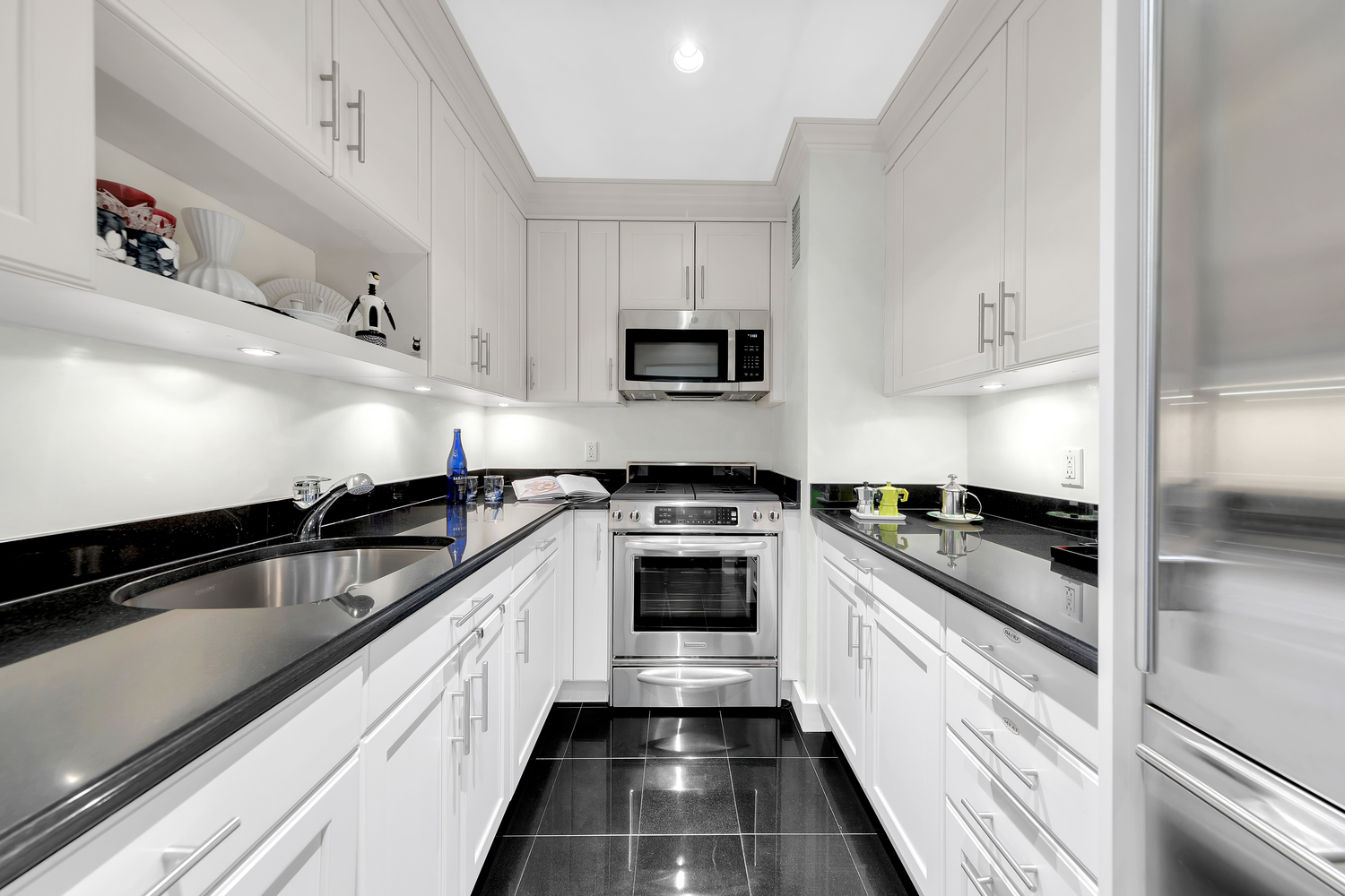 900 Park Avenue, Unit 10B Manhattan, NY 10075 - Photo 3 of 11 a kitchen with stainless steel appliances granite countertop a sink and a stove
