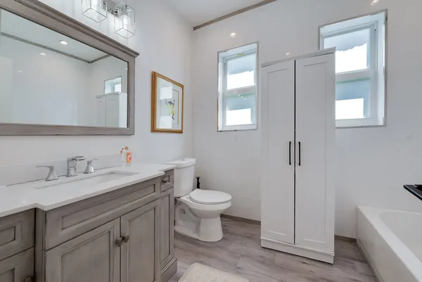 a bathroom with a toilet a sink a tub and mirror